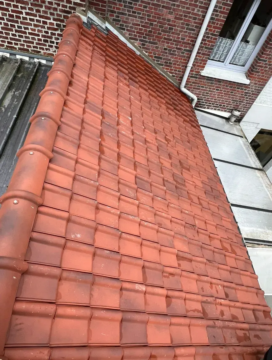 Couverture neuve en tuiles rouges au pied du même mur en briques