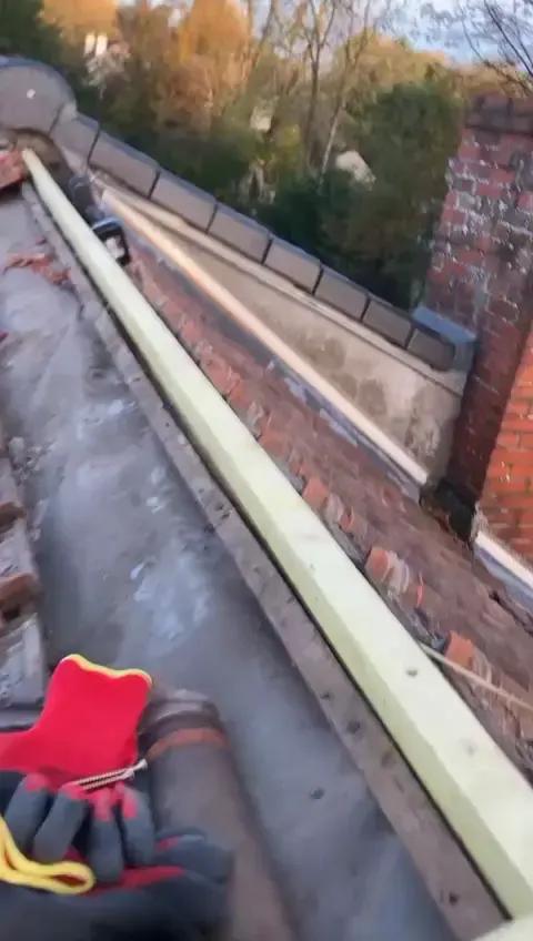 Rénovation d’un chéneau en cours, au pied d’un mur en briques